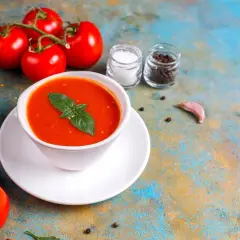 Zupa pomidorowa z bazylią, pomidory, oliwa, sól, pieprz i czosnek na kolorowym tle.